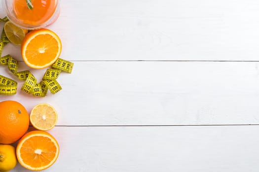 Fresh fruits with tape measure over white wooden background. Fitness concept. Top view. Copy space Flat lay