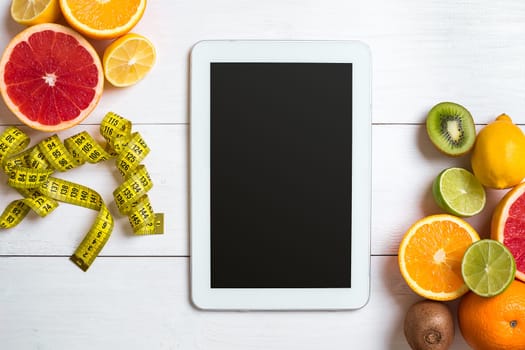 Fresh fruits with tape measure over white wooden background. Fitness concept. Top view. Copy space Flat lay