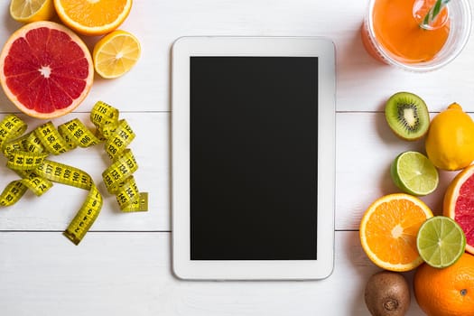 Fresh fruits with tape measure over white wooden background. Fitness concept. Top view. Copy space Flat lay