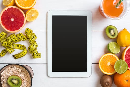 Fresh fruits with tape measure over white wooden background. Fitness concept. Top view. Copy space Flat lay