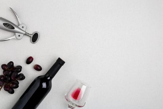 Overhead angled view of a large bottle of red wine, drinking glass on white background. Top view. Copy space