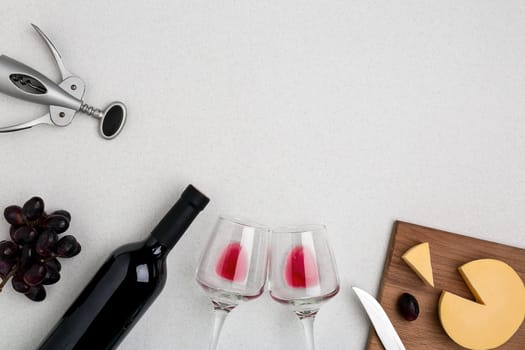 Two wine glasses with red wine,bottle of red wine and cheese on white background.Horizontal view from the top. Mock-up. Copy space. Flat lay