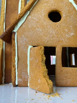 Child nibbled on a Christmas gingerbread house. Brown cookie house.