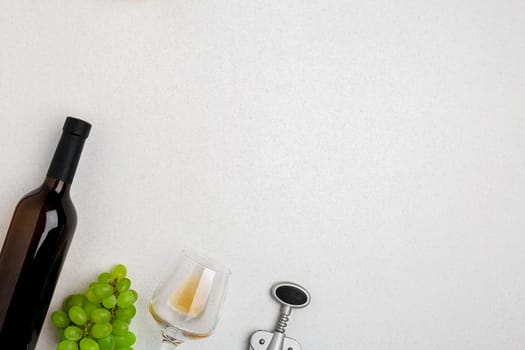 White wine bottle, glass and corkscrew over white background. Top view with copy space. Flat lay