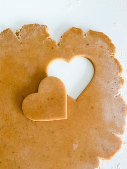 The process of making heart cookies. Top view of raw dough, rolling pin for baking