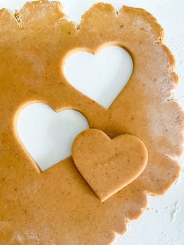 The process of making heart cookies. Top view of raw dough, rolling pin for baking