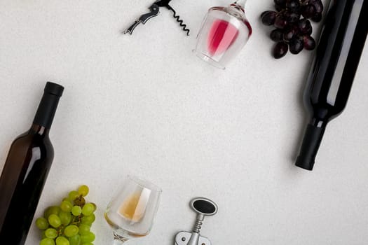 Glasses and bottles of red and white wine on white background from top view. Copy space