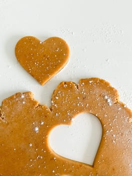 The process of cooking heart cookies. Top view of raw dough, rolling pin and baking cutter