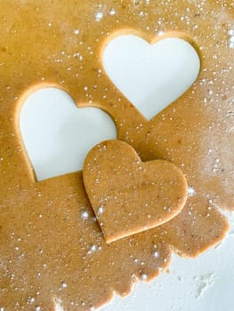 The process of cooking heart cookies. Top view of raw dough, rolling pin and baking cutter