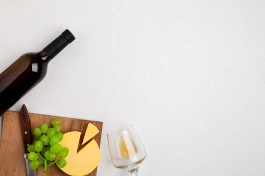 One wine glass with white wine, bottle of white wine, cheese on white background. Horizontal view from the top. Mock-up. Copy space. Flat lay