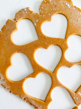 The process of cooking heart cookies. Top view of raw dough, rolling pin and baking cutter