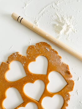 The process of cooking heart cookies. Top view of raw dough, rolling pin and baking cutter