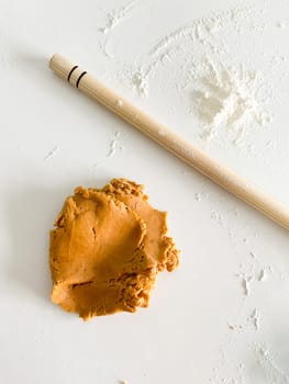 rolling pin and a piece of dough on a white table. cookie dough