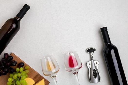 Glasses and bottles of red and white wine on white background from top view. Copy space