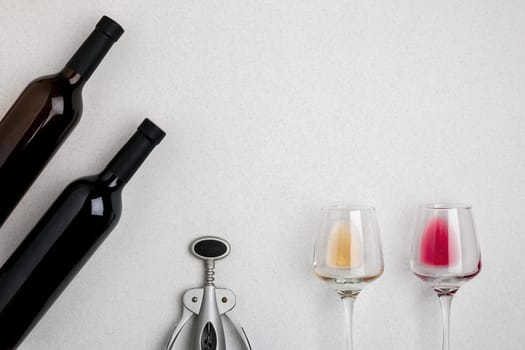 Glasses and bottles of red and white wine on white background from top view. Copy space