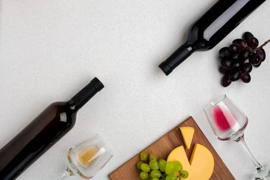 Two glasses of white and red wine, cheese and grapes. Two bottles of wine. Top view with copy space