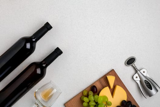 Glass of white wine, cheese and grapes. Two bottles of wine. Top view with copy space