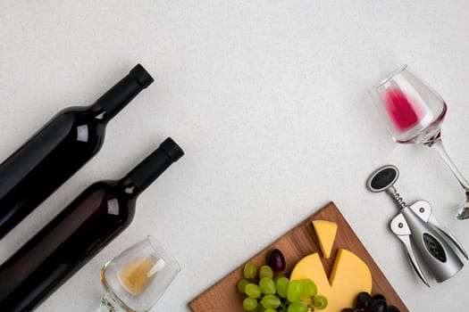 Two glasses of white and red wine, cheese and grapes. Two bottles of wine. Top view with copy space