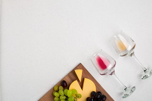 Two glasses of white and red wine, cheese and grapes. Top view with copy space