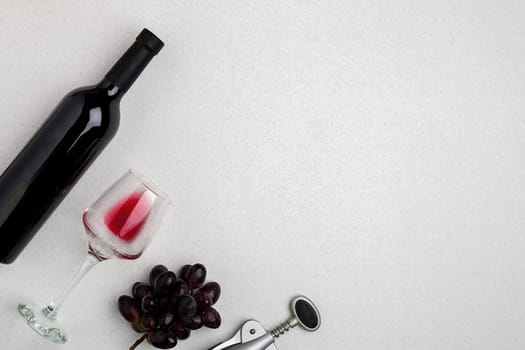Overhead angled view of a large bottle of red wine, drinking glass on white background. Top view. Copy space