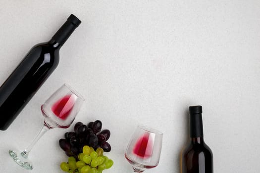 Glasses and bottles of red and white wine on white background from top view. Copy space