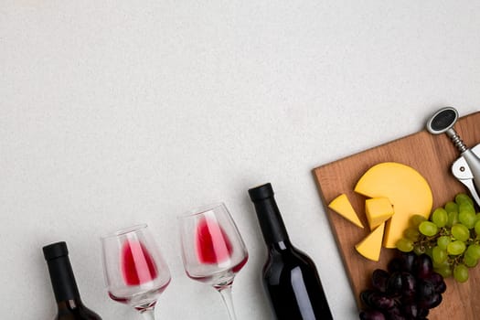 Glasses and bottles of red and white wine on white background from top view. Copy space