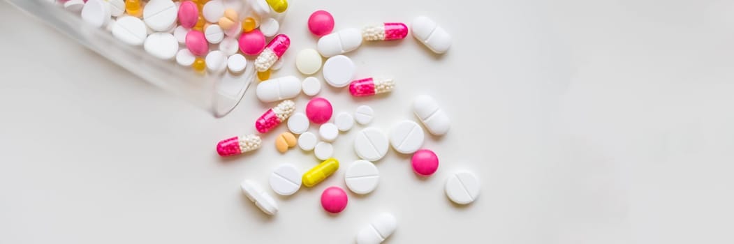 Pile of colorful medicine pills, white, blue, yellow and red, sitting on white background