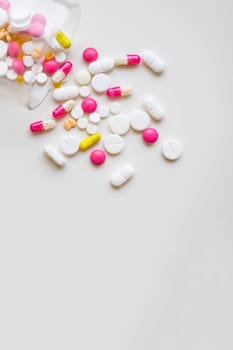 Pile of colorful medicine pills, white, blue, yellow and red, sitting on white background