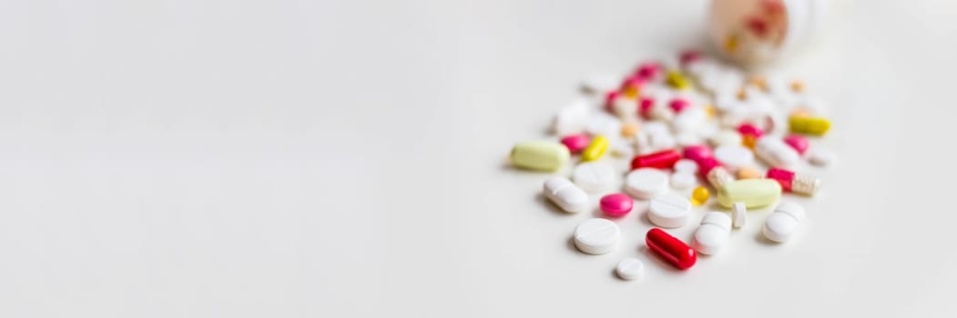 Pile of colorful medicine pills, white, blue, yellow and red, sitting on white background