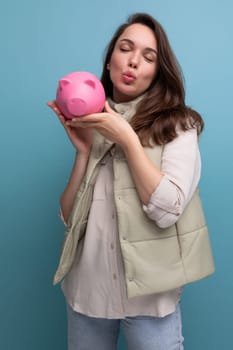 young brunette woman with a pink piggy bank in her hands.