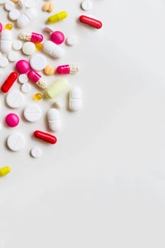 Pile of colorful medicine pills, white, blue, yellow and red, sitting on white background