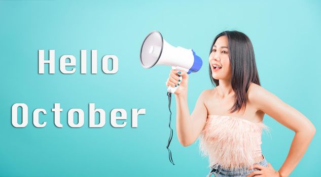 Hello October, Smiling face portrait Asian beautiful young woman her using megaphone to say hello studio shot isolated on blue background