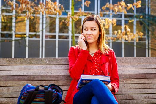 A young female college student study books outside of library.