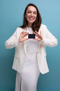 brunette woman in a dress uses electronic money transfer using a card and a smartphone.