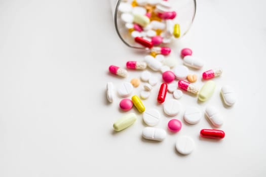 Many white tablets spilling out of package, Close up pills spilling out of pill bottle on blue background.