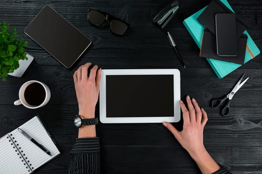 Overhead view of businesswoman working at computer in office against a dark background. Women's hands. Copy space