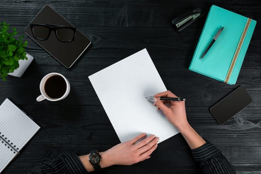 Overhead view of businesswoman working at computer in office against a dark background. Women's hands. Copy space