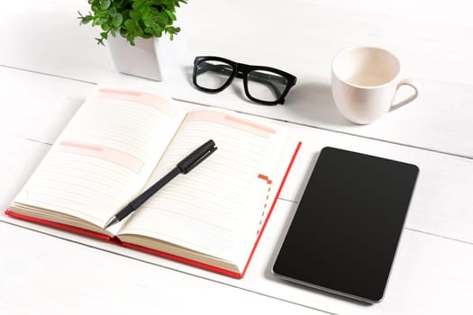 Stylish minimalistic workplace with tablet and notebook and glasses in flat lay style. White background. Top view. Copy space