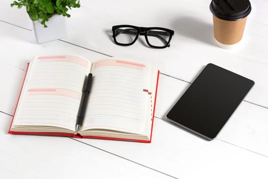 Stylish minimalistic workplace with tablet and notebook and glasses in flat lay style. White background. Top view. Copy space