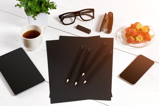 Modern workplace with digital tablet computer and mobile phone, cup of coffee, pen and empty sheet of paper. Top view and copy space for text. sun flare