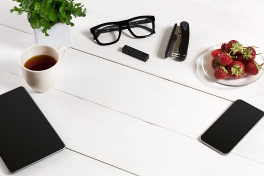 Modern workplace with digital tablet computer and mobile phone, cup of coffee and flower on white background. Top view and copy space for text