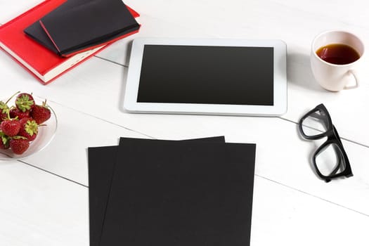 Stylish minimalistic workplace with tablet and notebook and glasses in flat lay style. White background. Top view. Copy space