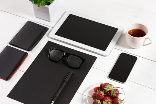 Modern workplace with digital tablet computer and mobile phone, cup of coffee, pen and empty sheet of paper. Top view and copy space for text