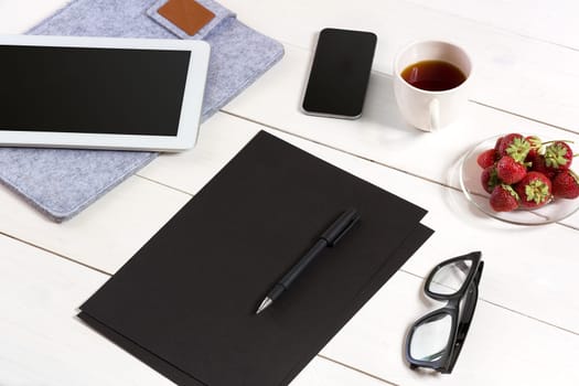 Modern workplace with digital tablet computer and mobile phone, cup of coffee, pen and empty sheet of paper. Top view and copy space for text