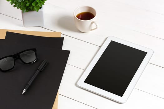 Modern workplace with digital tablet computer and mobile phone, cup of coffee, pen and empty sheet of paper. Top view and copy space for text