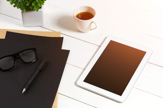 Modern workplace with digital tablet computer and mobile phone, cup of coffee, pen and empty sheet of paper. Top view and copy space for text