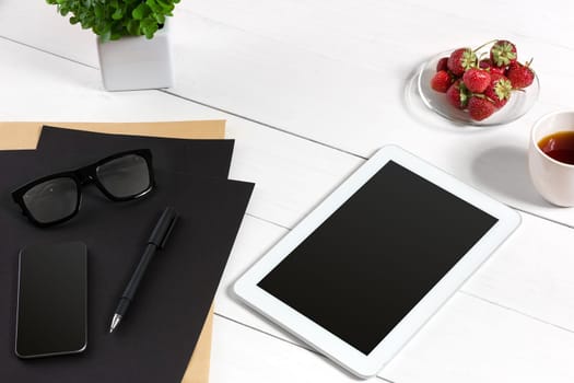 Modern workplace with digital tablet computer and mobile phone, cup of coffee, pen and empty sheet of paper. Top view and copy space for text