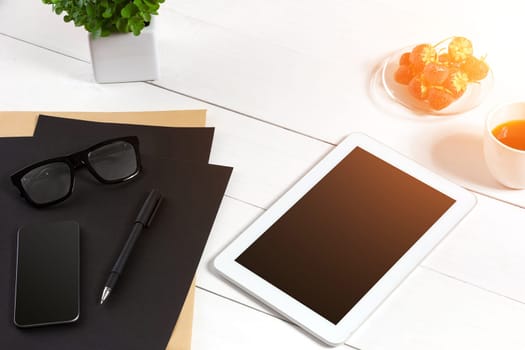 Modern workplace with digital tablet computer and mobile phone, cup of coffee, pen and empty sheet of paper. Top view and copy space for text