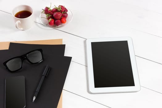 Tablet, blank sheet, glasses and coffee cup on office wooden table. White background. Top view. Copy space