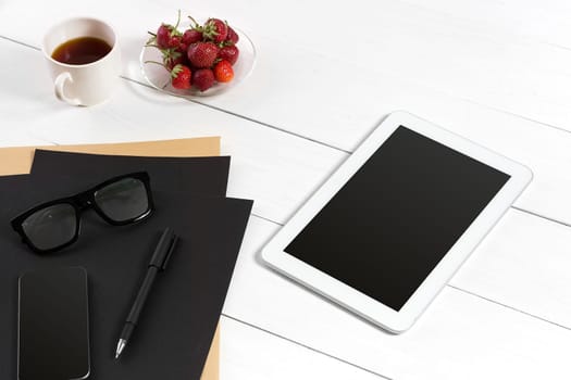 Modern workplace with digital tablet computer and mobile phone, cup of coffee, pen and empty sheet of paper. Top view and copy space for text